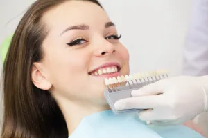 Smiling woman having teeth compared to tooth color selector